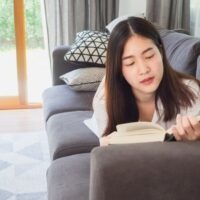 自宅で読書をしている若い女性