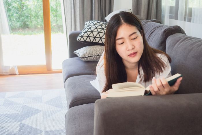 自宅で読書をしている若い女性